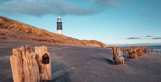 A lighthouse, viewed from a sandy beach