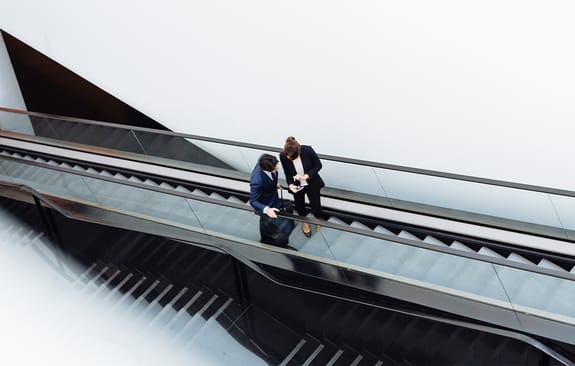 Businessman and businesswoman chatting on an escalator