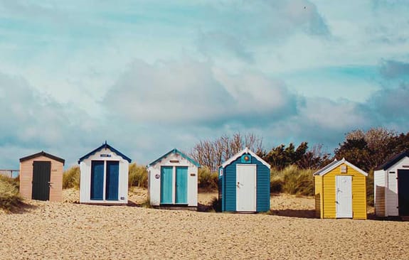 Colourful beach huts on a sandy beach in front of dunes