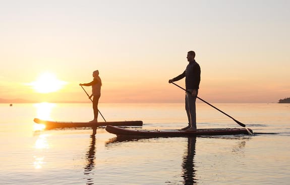 Two people on paddleboards on the sea during sunset