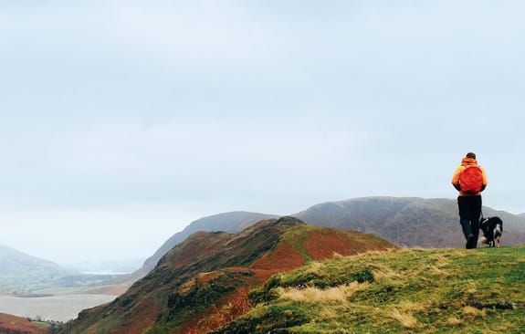 Man walking his dog looking over the foggy hills