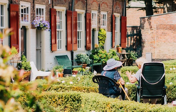 Two old ladies seated swap stories in the garden