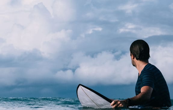 Surfer in the ocean looks back at next wave