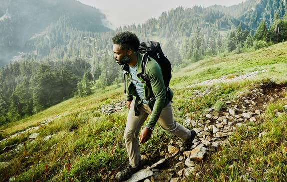 man walking down a hill in the countryside