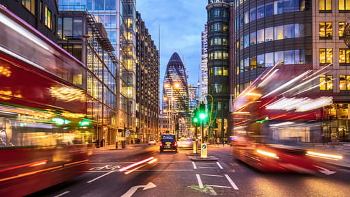 Buses rush through the City of London at dusk