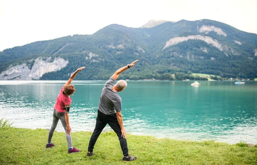 A couple doing yoga by the edge of a lake