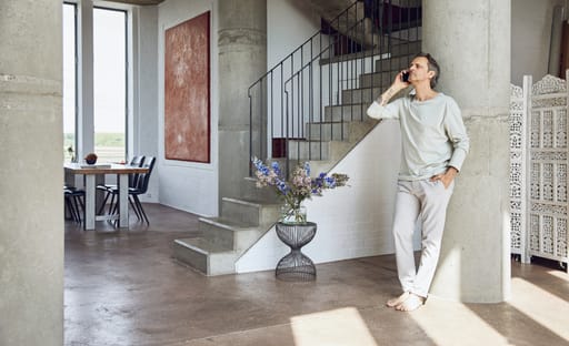 A man talks on the phone while leaning on a concrete column in his minimalist holiday home
