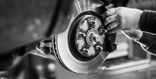 A factory worker fits a disk break on a car