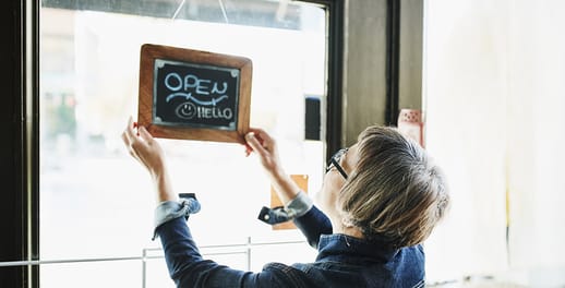 Women turning an open-for-business sign