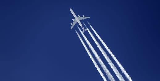 Aeroplane flying through sky with jetstreams behind it