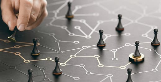Hand moving chess pieces on a black board