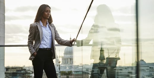 Business woman standing on glass balcony with London skyline