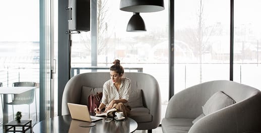 Young business woman sitting on couch, writing in notebook