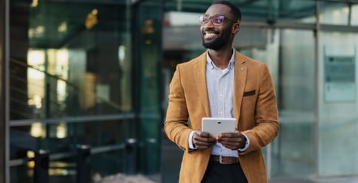Business man smiling walking outside the office with a tablet