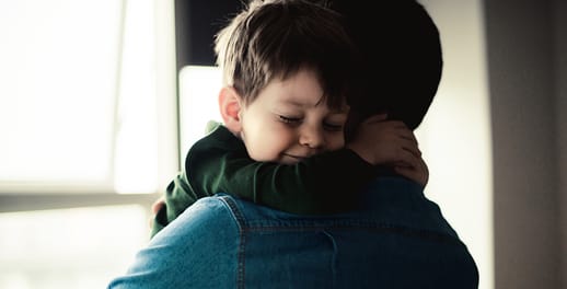 Toddler hugging his father's neck as he's being carried