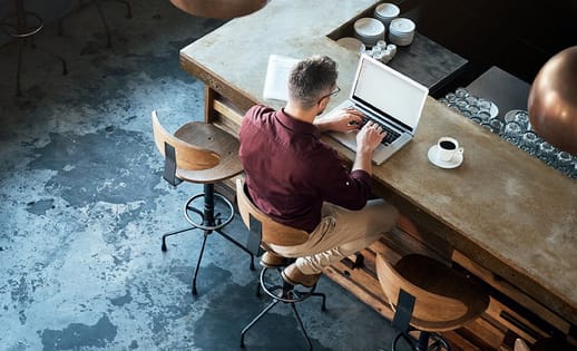 male working on laptop in a restaurant with a coffee