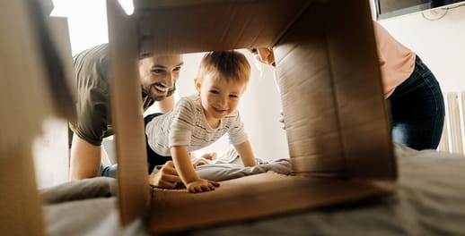 baby crawling through a cardboard box with family