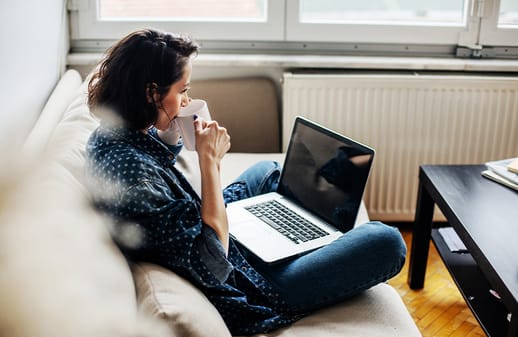 Female working on laptop on her lap on a couch