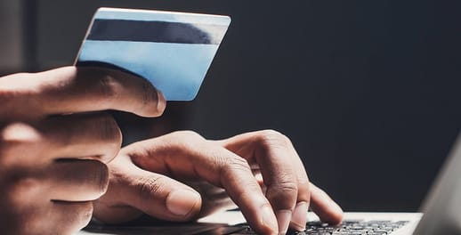 Person holding bank card working at laptop