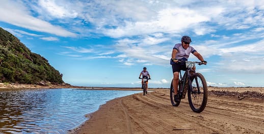 mountain bikers riding along coast