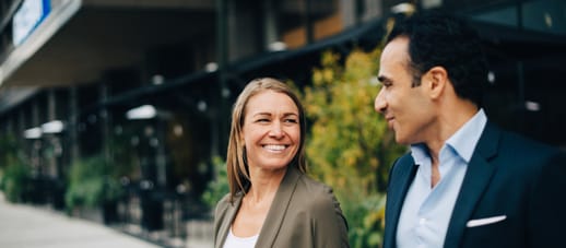 Two corporate workers walking onto the footpath together