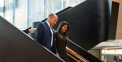 Two Investec members of staff walking down staircase in office