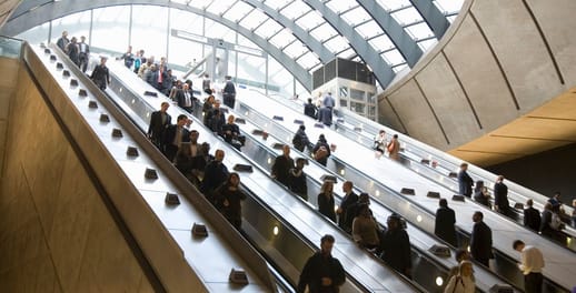 Corporate commuters on esclators to the Canary Wharf underground in London