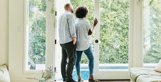 A couple look out from their house into their garden