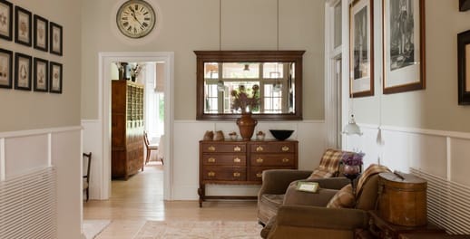 The hallway of a luxury house featuring photos and leather arm chairs