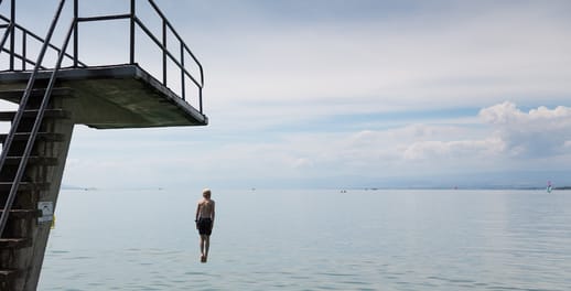 A man jumps off a diving board and into the sea