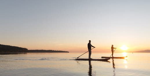 Two people on paddleboards on the sea during sunset 