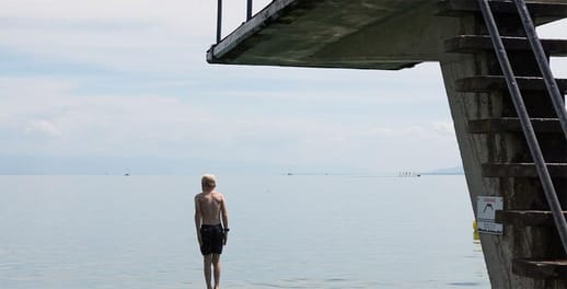 Man standing next to a diving board over the sea