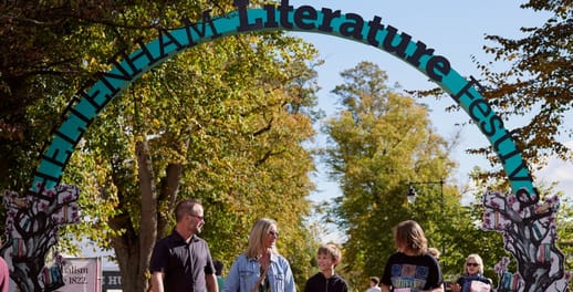 A family walk under the entrance to the Cheltenham Literature Festival