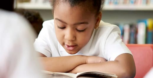 Young girl reading a book in library