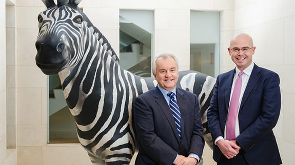 Michael Cullen and Derek Byrne standing infront of a Zebra