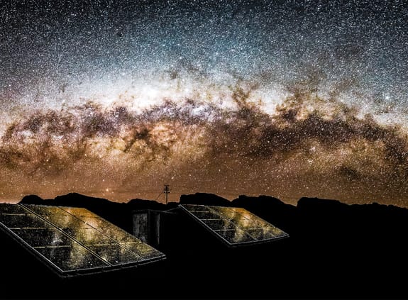 solar panels in front of galaxy