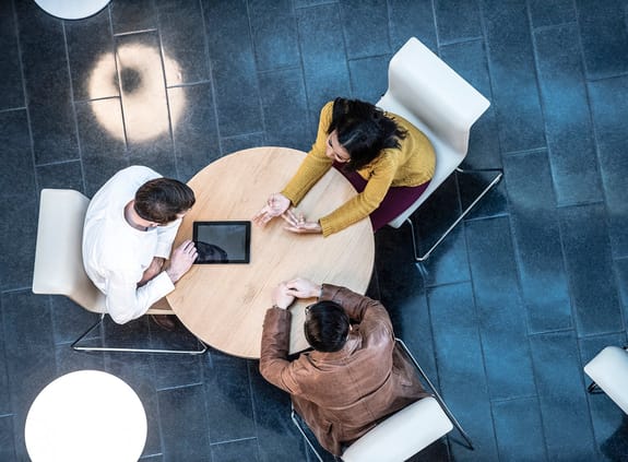 Three people in discussion at round table