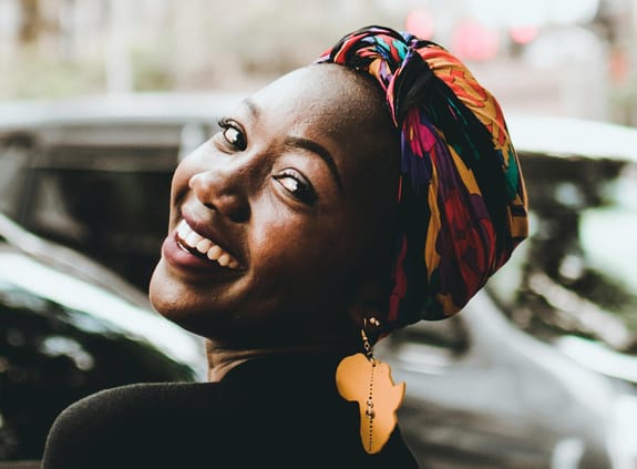 Smiling African woman wearing earrings shaped like Africa
