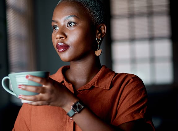 Woman staring out window, holding coffee cup