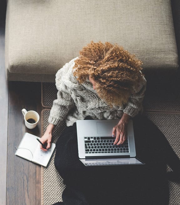 female working on laptop sitting on the floor at home