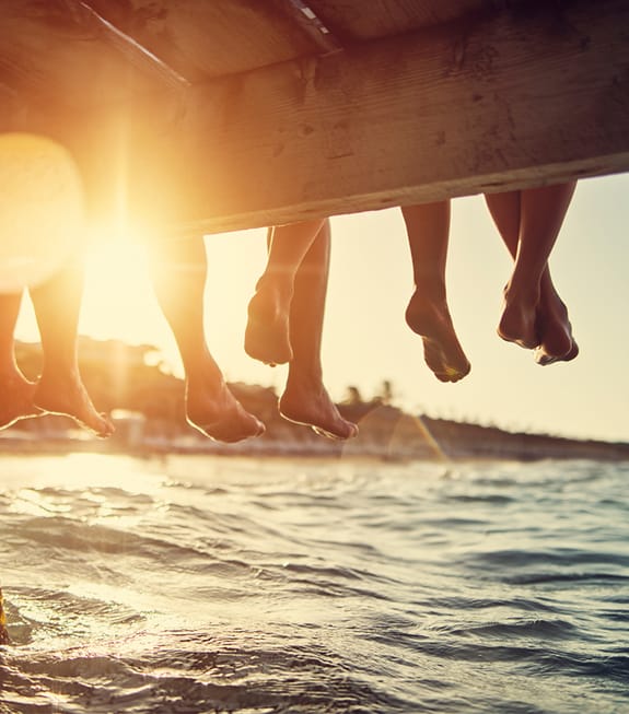 multiple legs dangling over a pier above the water