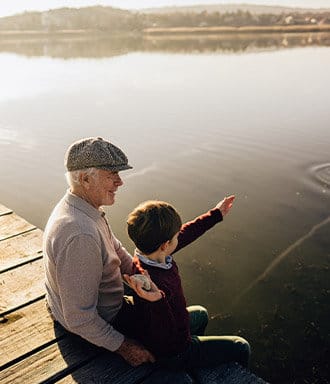 Grandson throwing rocks into water off the dock with his grandad