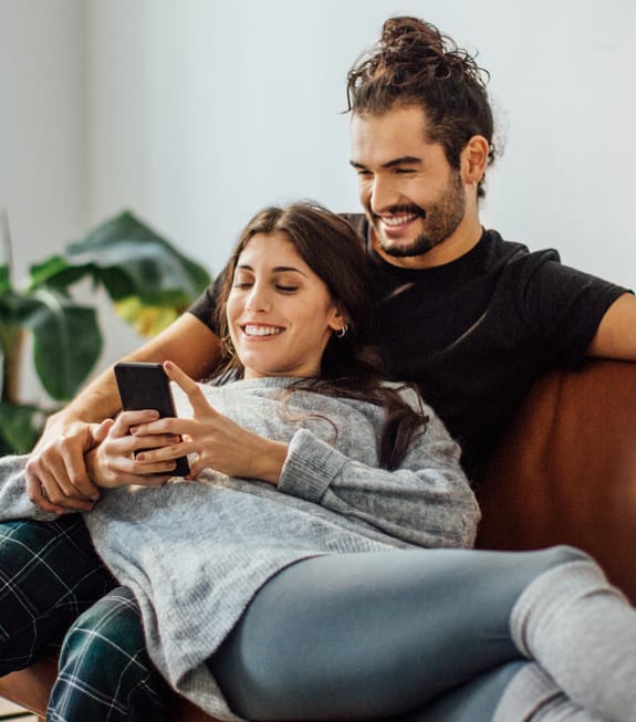 Couple lounging while scrolling through their Investec Rewards benefits