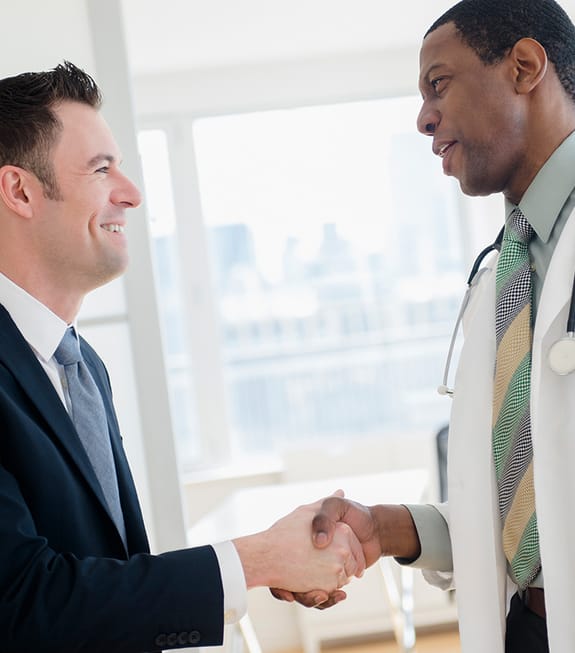 Medical professional in healthcare shaking business man's hand