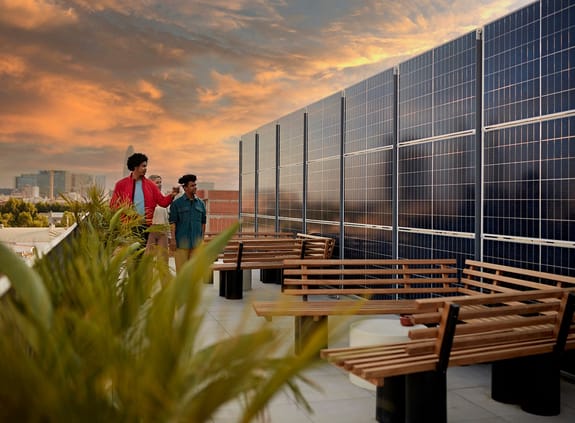 Wind turbines with solar panels on people on rooftop deck of office building admiring commitment to renewable energy