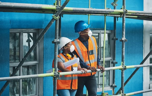 male and female standing on scaffolding surveying the build