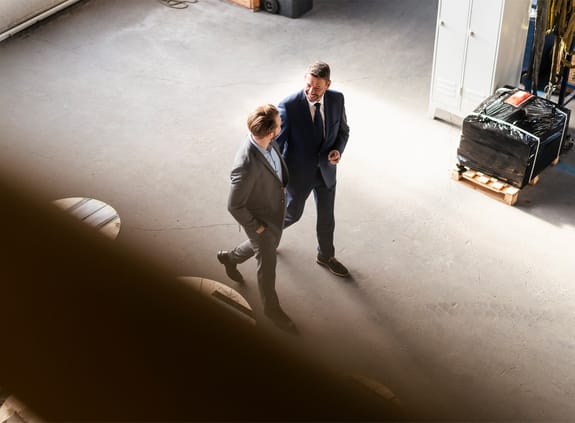 Bird's eye view of two businessmen walking and talking in a factory