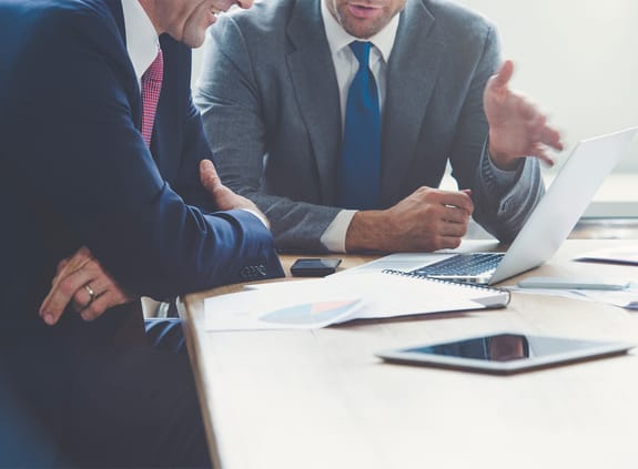 Businessmen in a meeting looking at a laptop