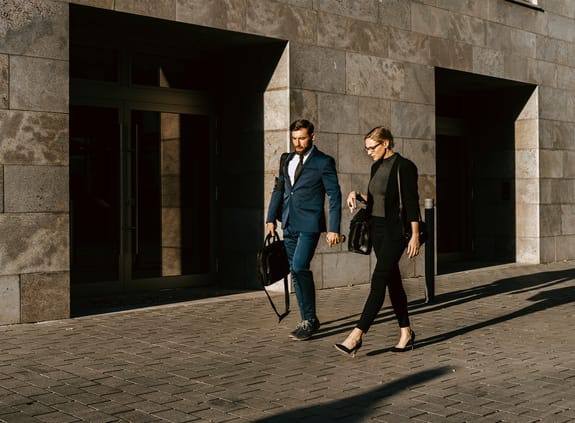 female and male colleagues discussing while walking on footpath in city