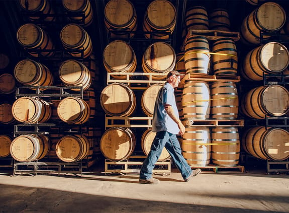 male walking near barrels in distillery